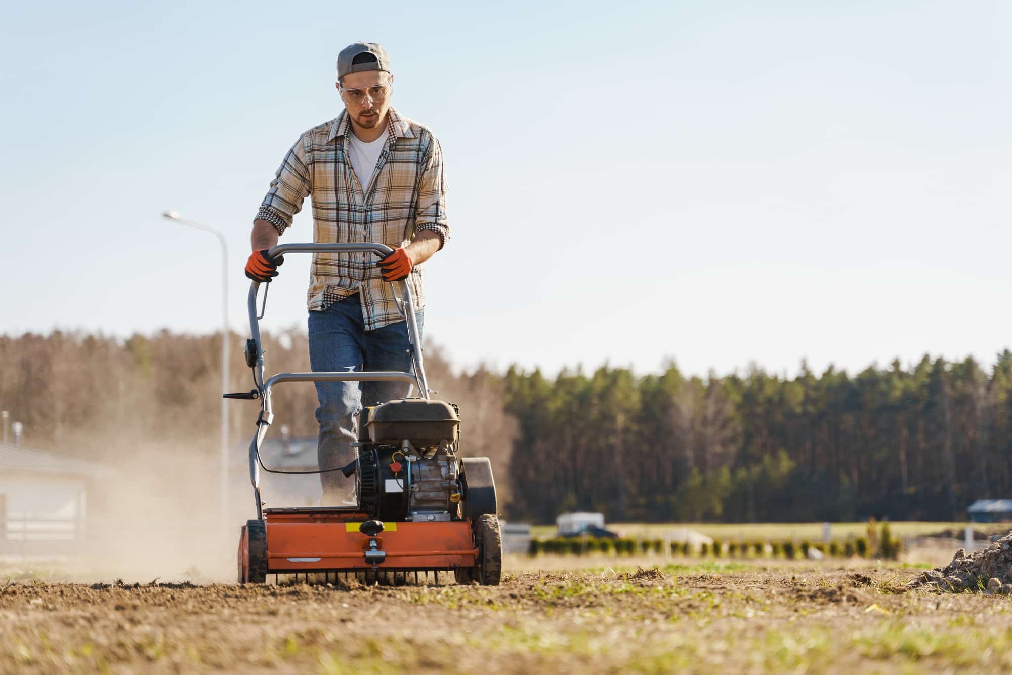 Man using aerator machine to scarification and aeration of lawn or meadow