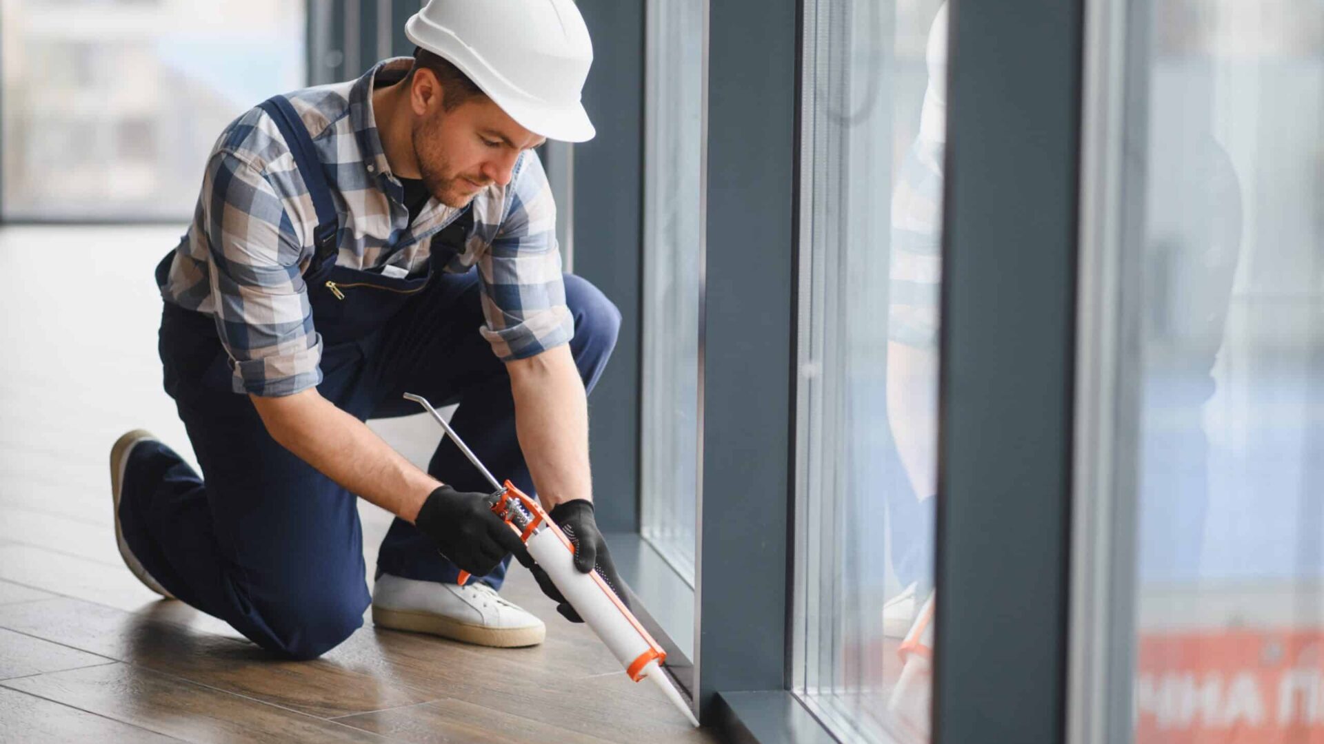 Construction worker applying sealant to window frame